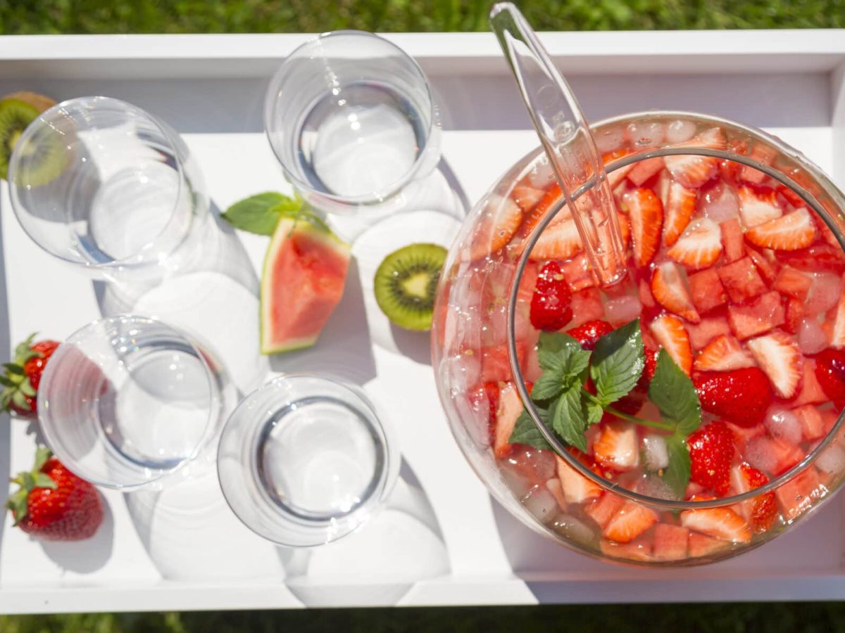 Spritzige Wassermelonen-Bowle in großem Gefäß, daneben Gläser