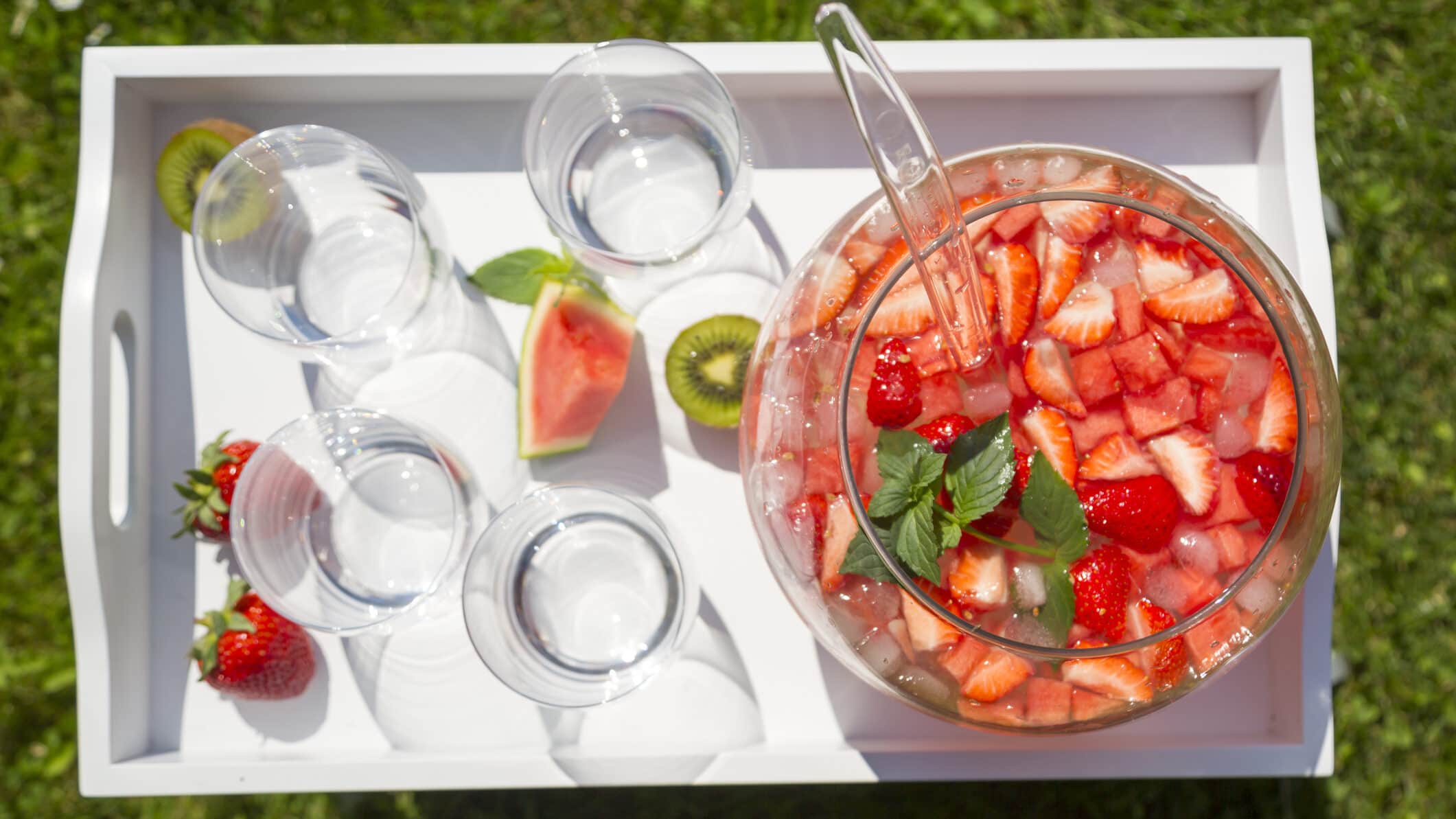 Spritzige Wassermelonen-Bowle in großem Gefäß, daneben Gläser