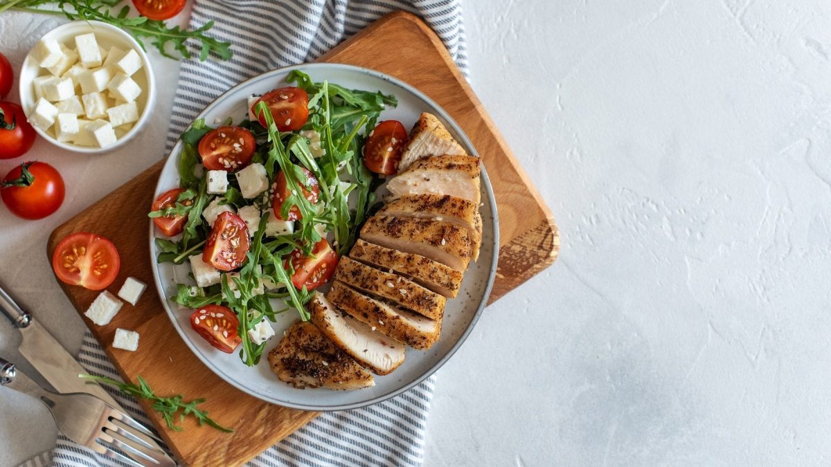 Holzbrett und Teller mit Sommer-Salat mit Pute