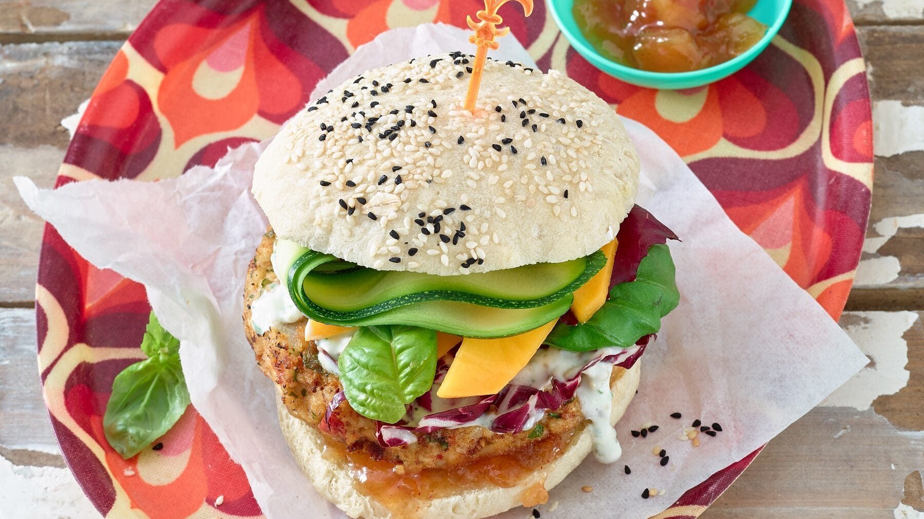 Veganer Burger mit Kichererbsen-Patty auf Papierunterlage und rotem Tablett
