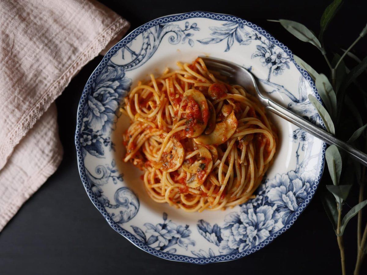 Spaghetti mit Champignonsauce auf weißem Teller mit Blumenmuster