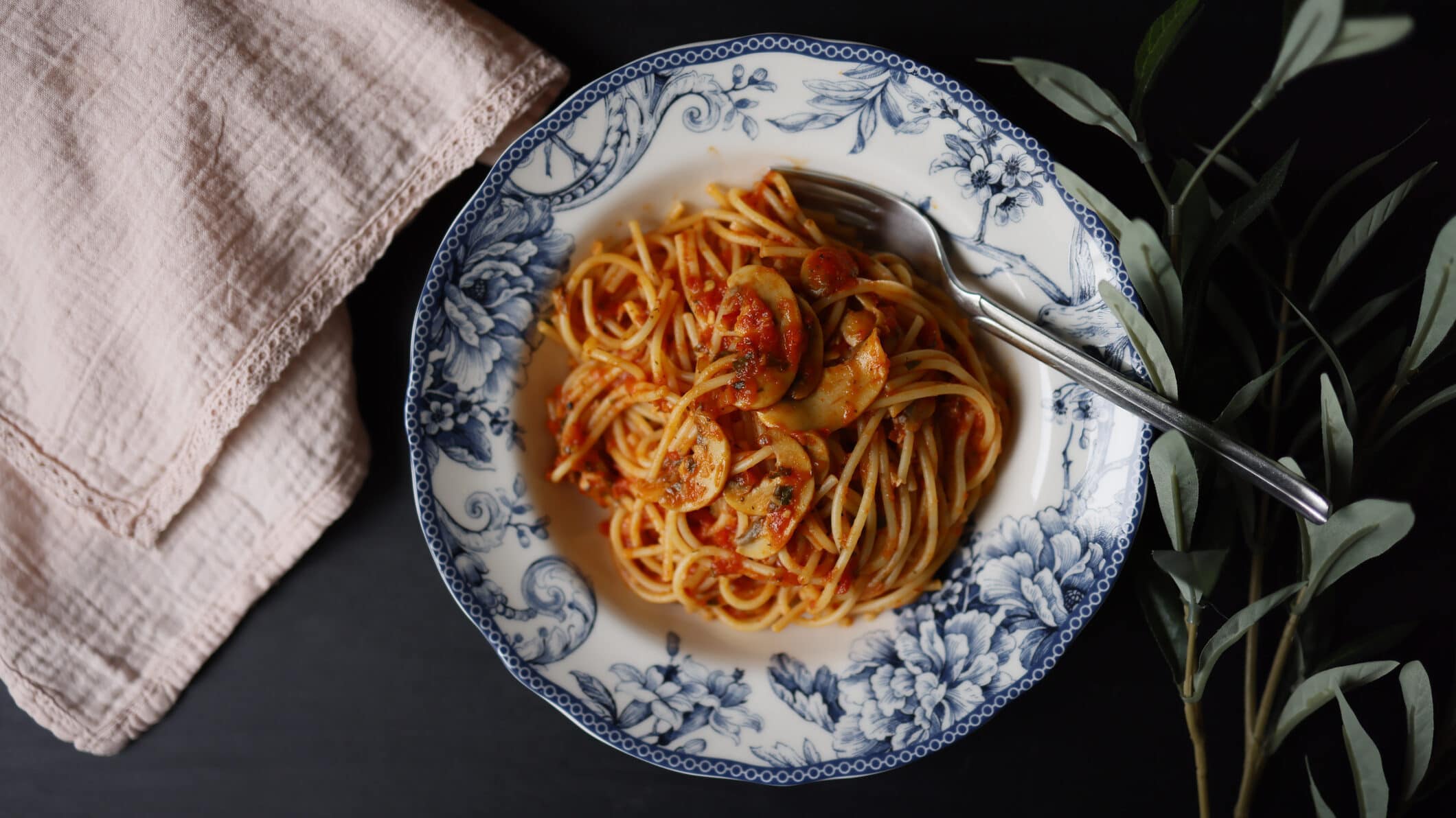 Spaghetti mit Champignonsauce auf weißem Teller mit Blumenmuster