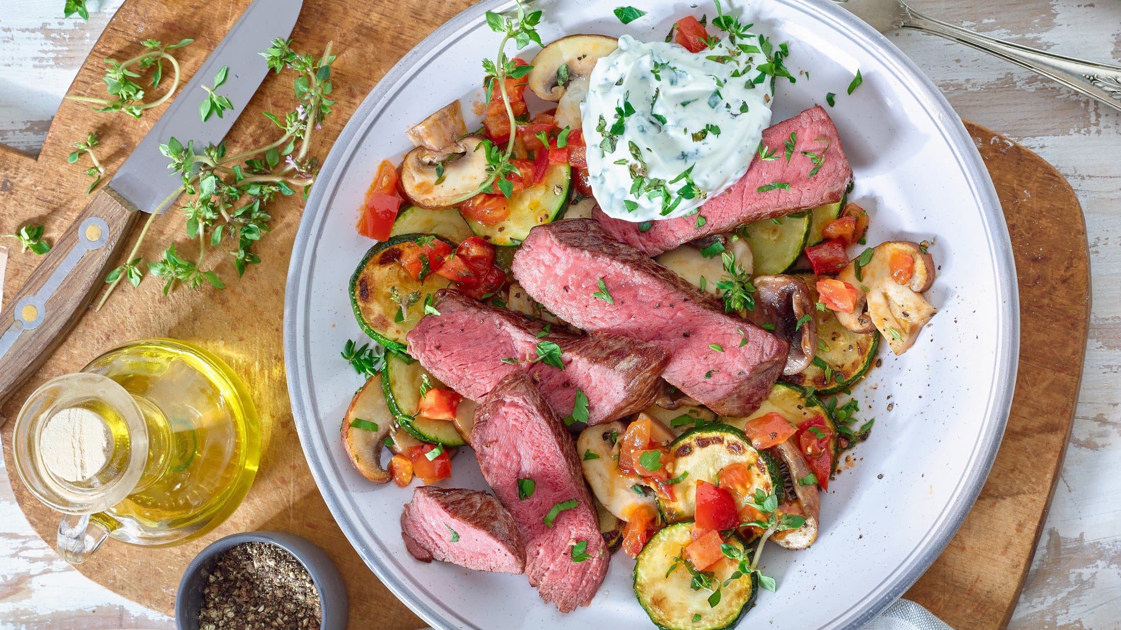 Steakstreifen auf mediterranem Gemüse auf Teller serviert.