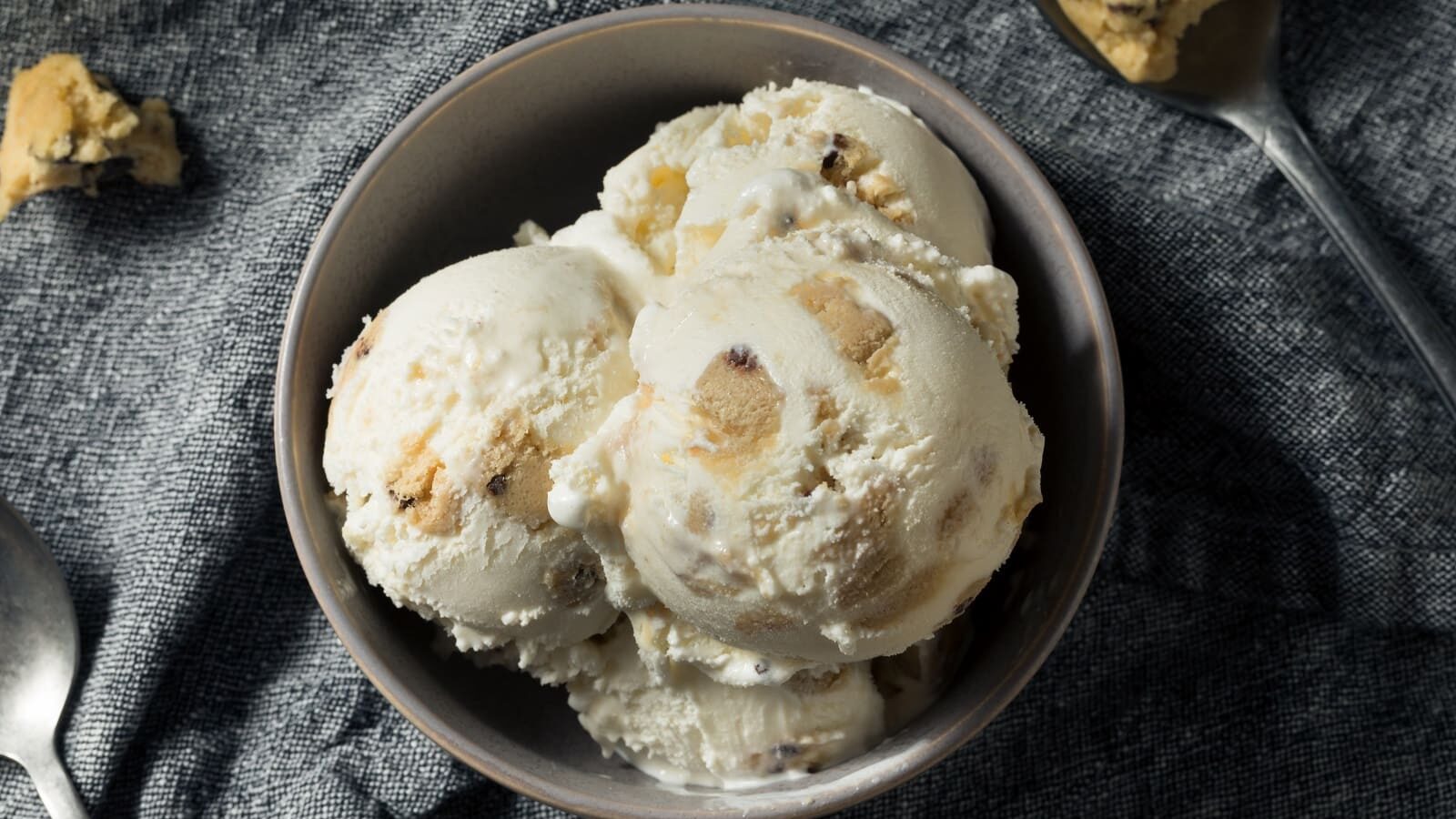 Vier Bällchen Cookie-Dough-Eis in einer Schüssel vor grauem Hintergrund, von oben fotografiert