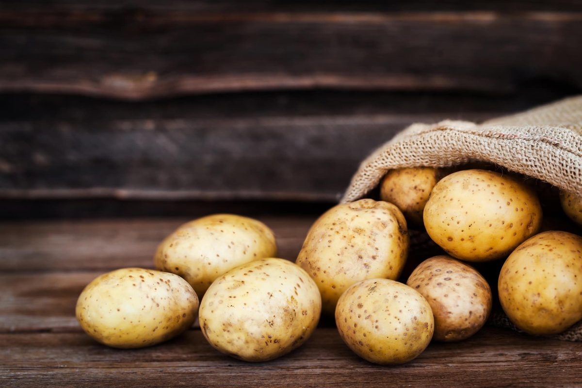 Lebensmittel, die kein Licht vertragen: ein umgekippter Sack Kartoffeln vor einem Holzhintergrund