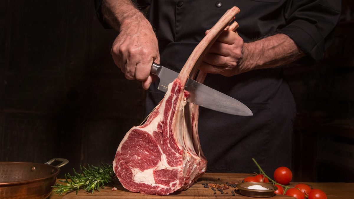 Fleisch wird mit Messer von Knochen getrennt.