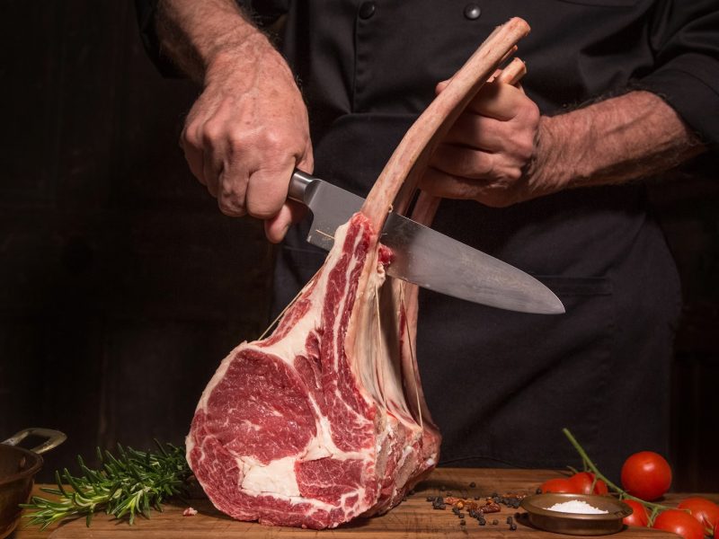 Fleisch wird mit Messer von Knochen getrennt.