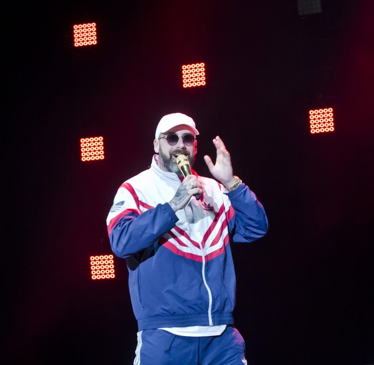 Rapper Sido mit Trainingsanzug, Kappe, Sonnenbrille und Mikrofon in der Hand auf der Bühne.