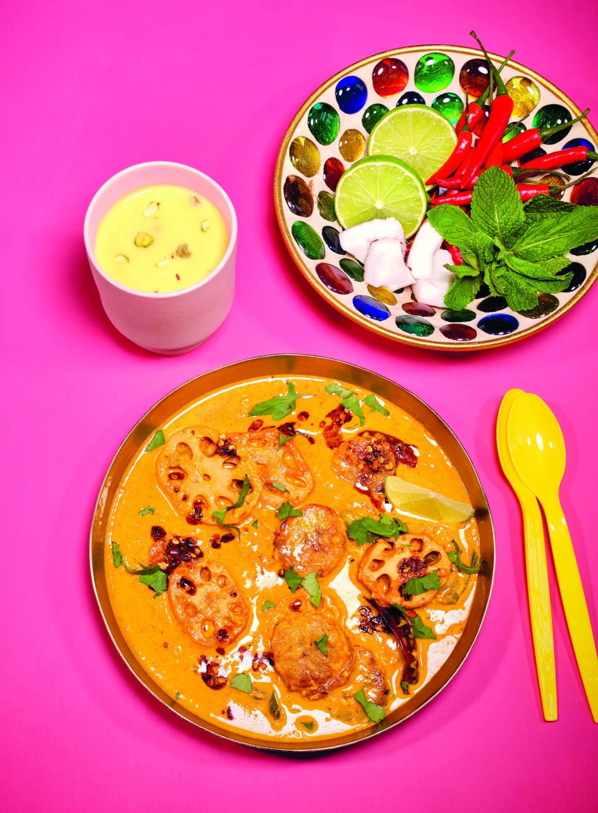 Das Lotuswurzel-Curry angerichtet in einer Schale, dazu als Topping Kokosflocken, Limette und Chilis.