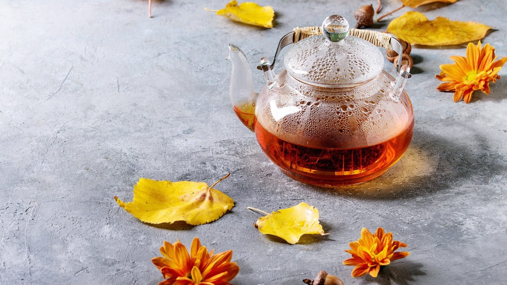 Da kommt heiße Herbststimmung auf: Unser Vanille-Kokos-Tee brüht in der Glas-Teekanne. Ringsum liegen bunte Blätter.