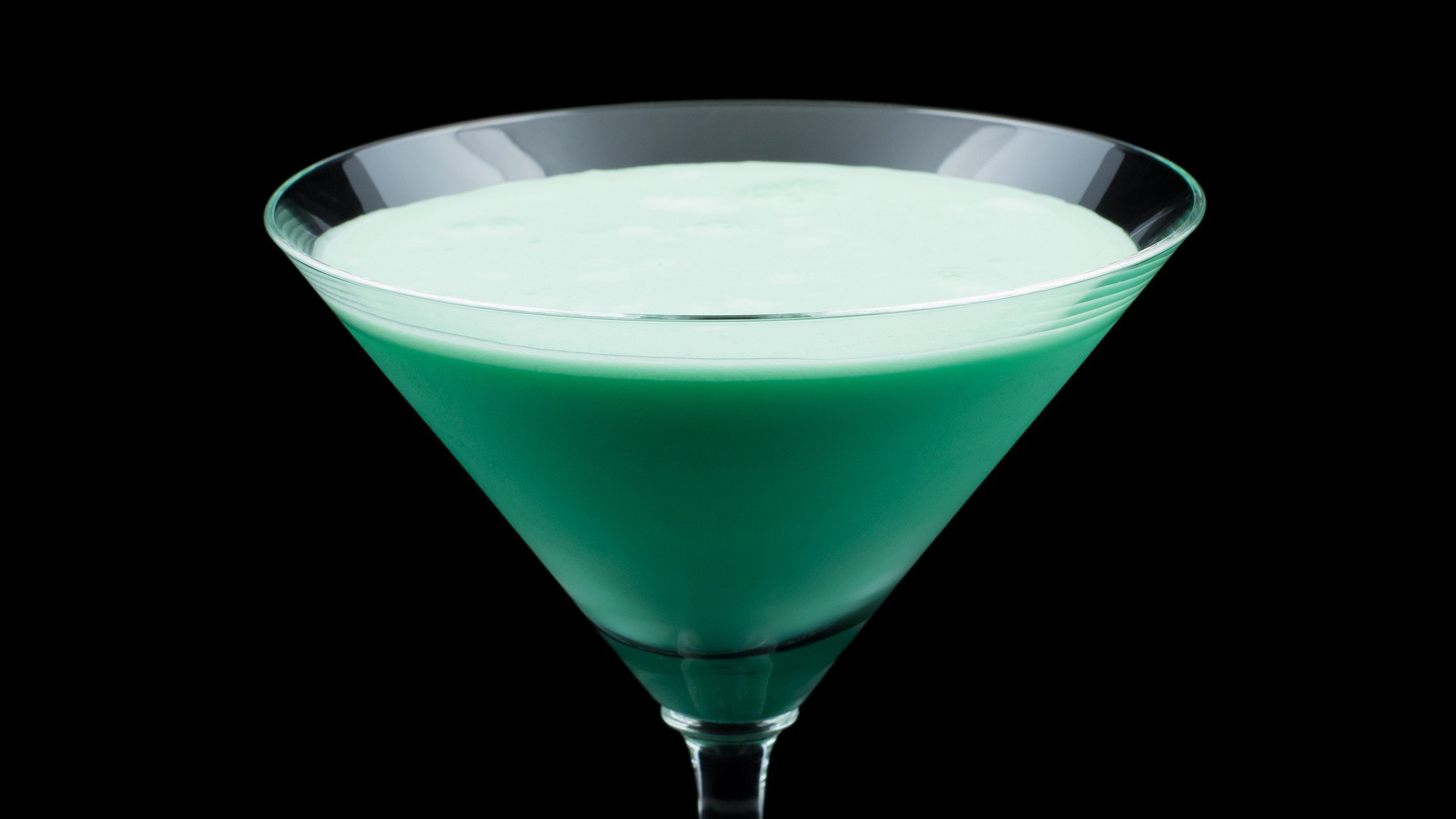 Grasshopper in einem Martini-Glas vor dunklem Hintergrund
