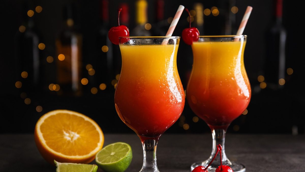 Zwei Gläser Tequila Sunrise dekoriert mit Cocktailkirschen und Trinkhalmen in edlem Ambiente