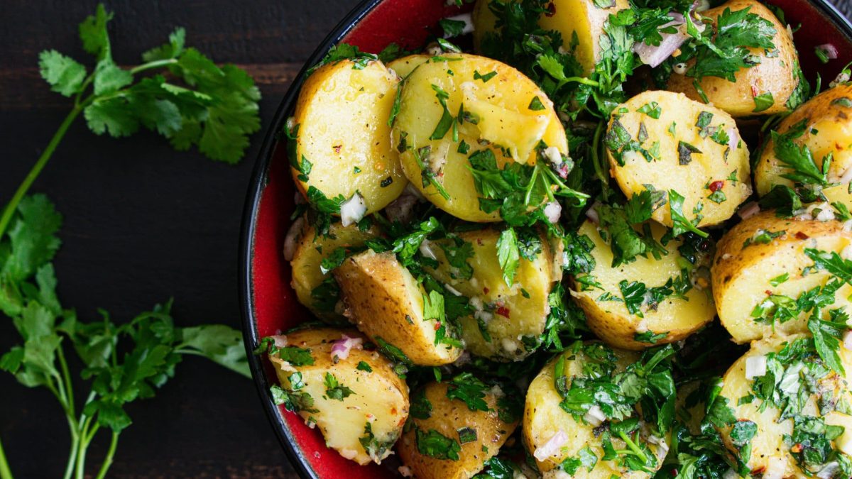Eine Schale Kartoffelsalat mit Schalottendressing und Petersilie.