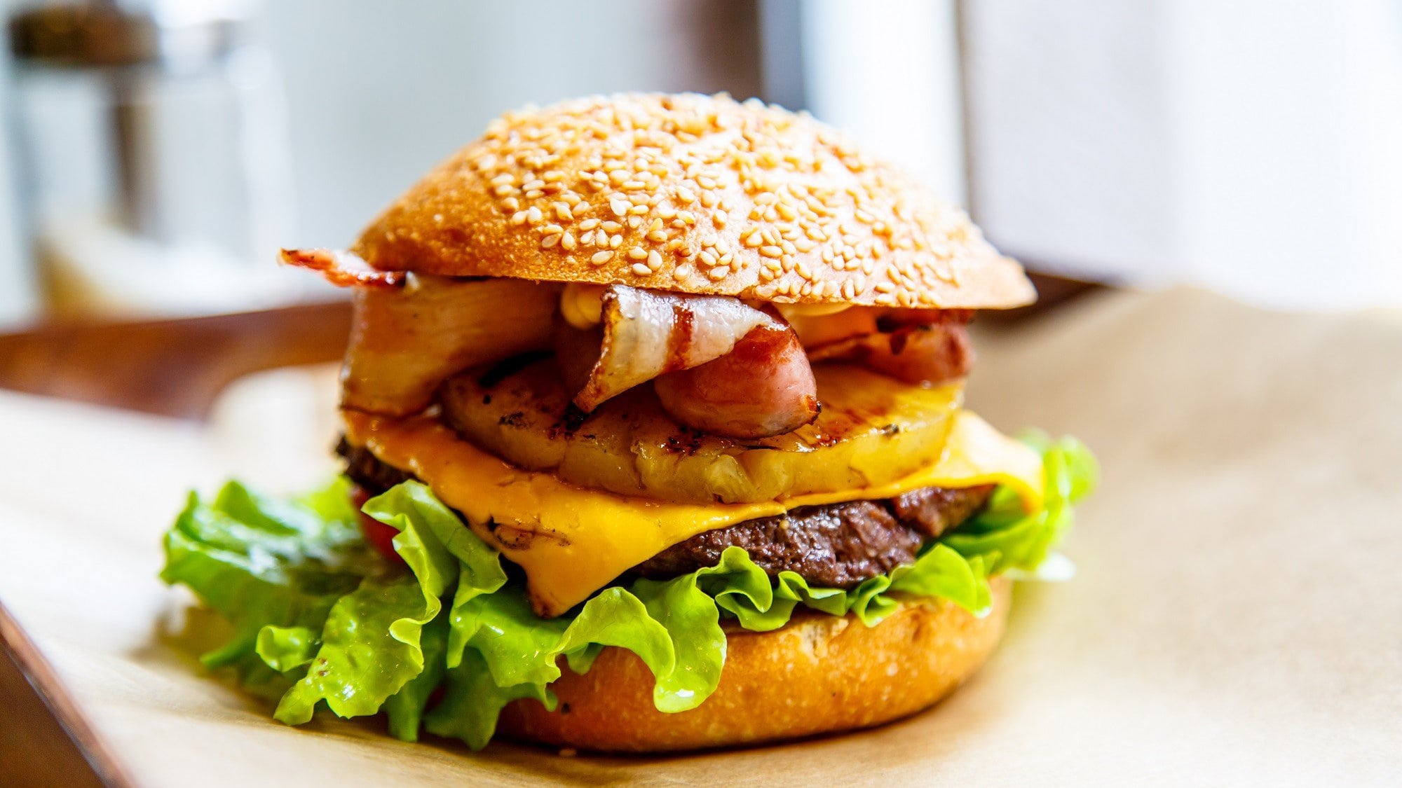Big Kahuna Burger Pulp Fiction auf einer hellen Unterlage. Der Burger ist belegt mit Salat, Ananas, Bacon und Rindfleiscj.