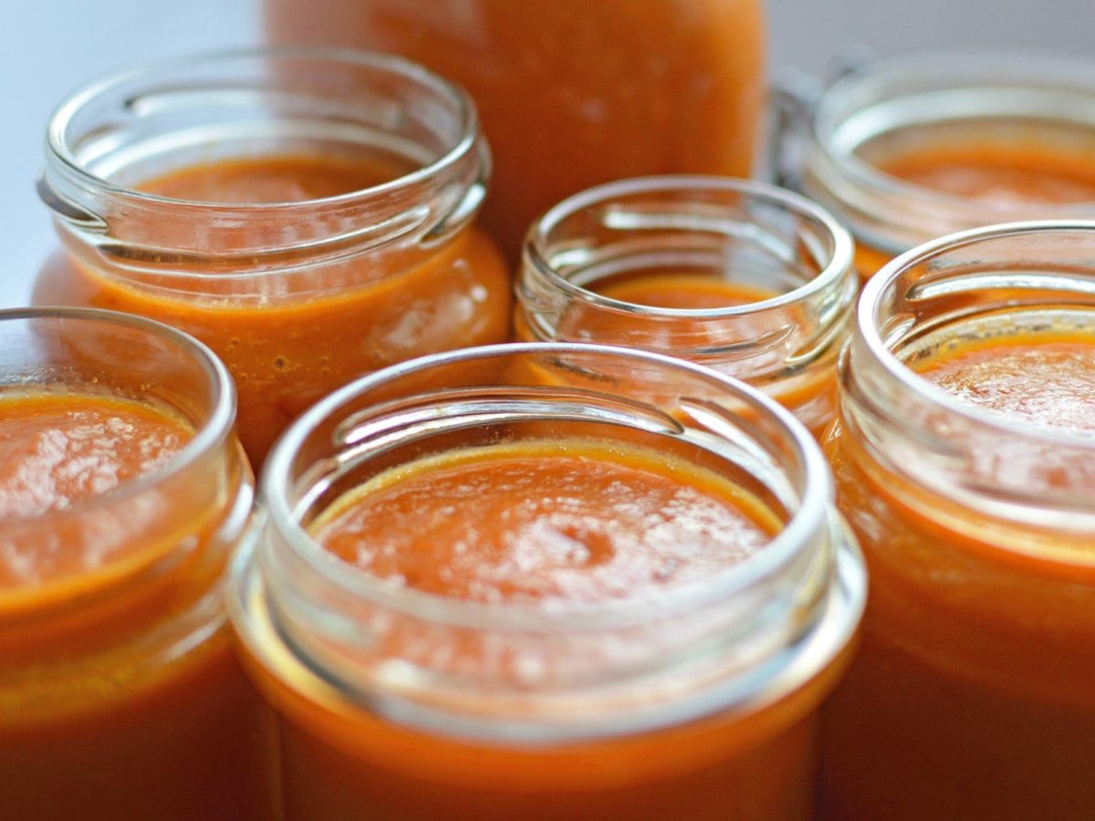 Orange-hellrote Habanero Hot Sauce in verschieden großen offen Einmachgläsern aus der Frontalsicht.