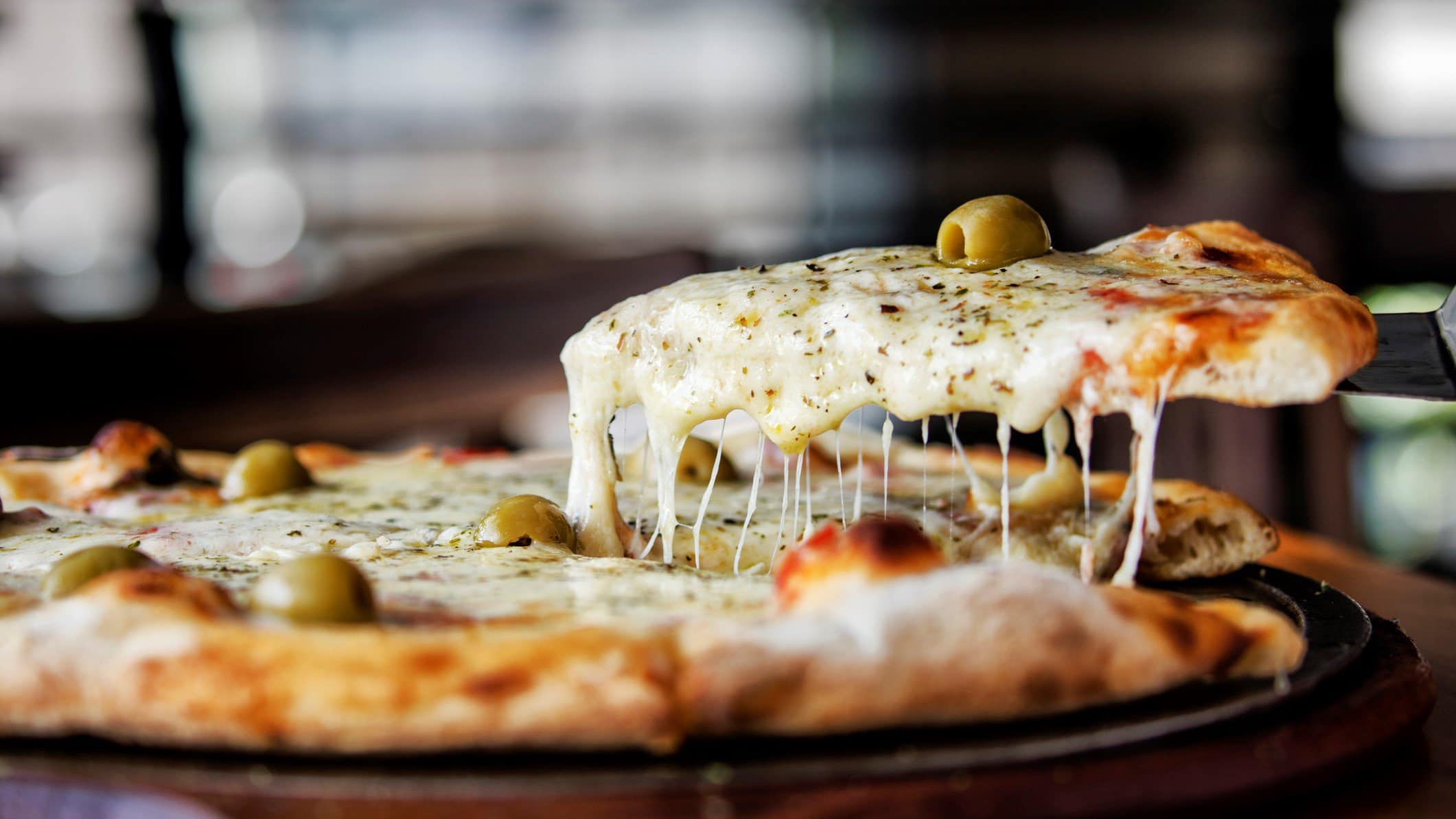 Pizza mit geschmolzenem Käse, Oliven und Pizzagewürz