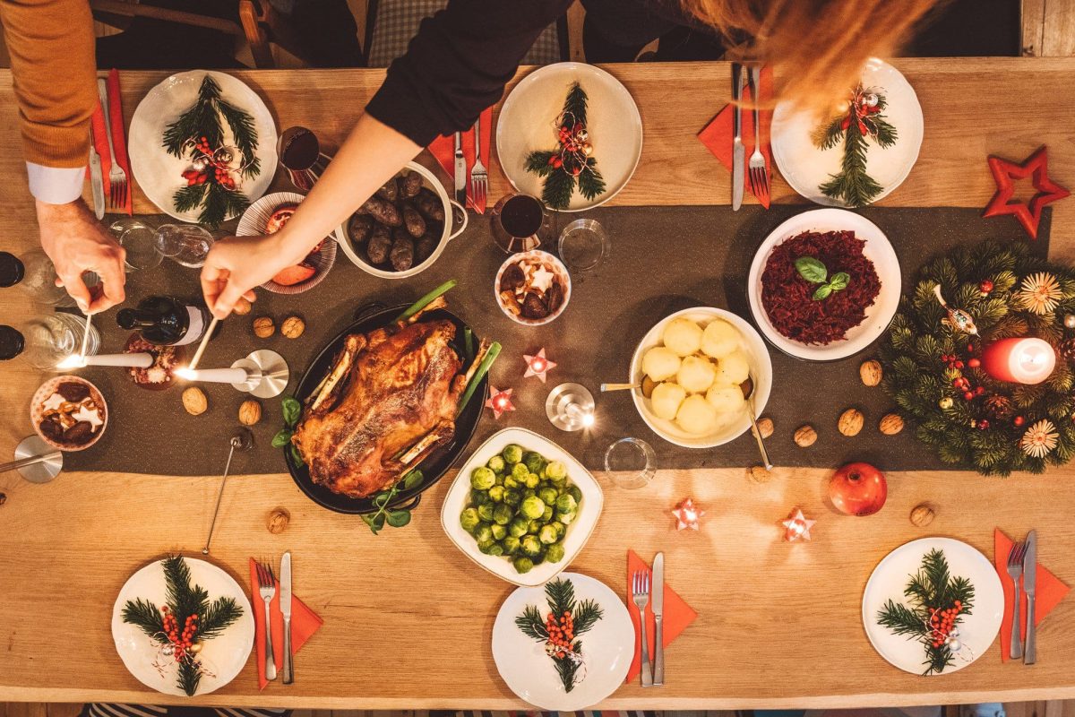 Beilagen zum Weihnachtsmenü gedekcter Tisch mit Gänsebraten, Wein, Gläsern und Beilagen. Draufsicht.