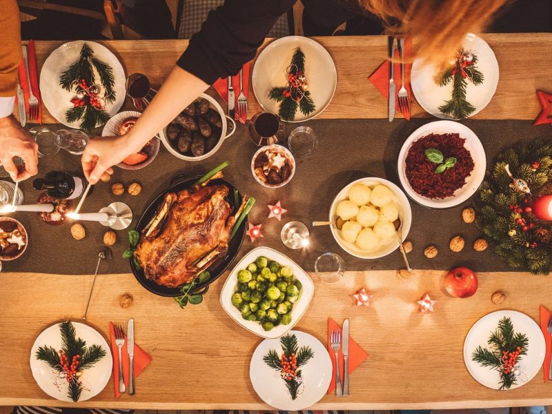Beilagen zum Weihnachtsmenü gedekcter Tisch mit Gänsebraten, Wein, Gläsern und Beilagen. Draufsicht.