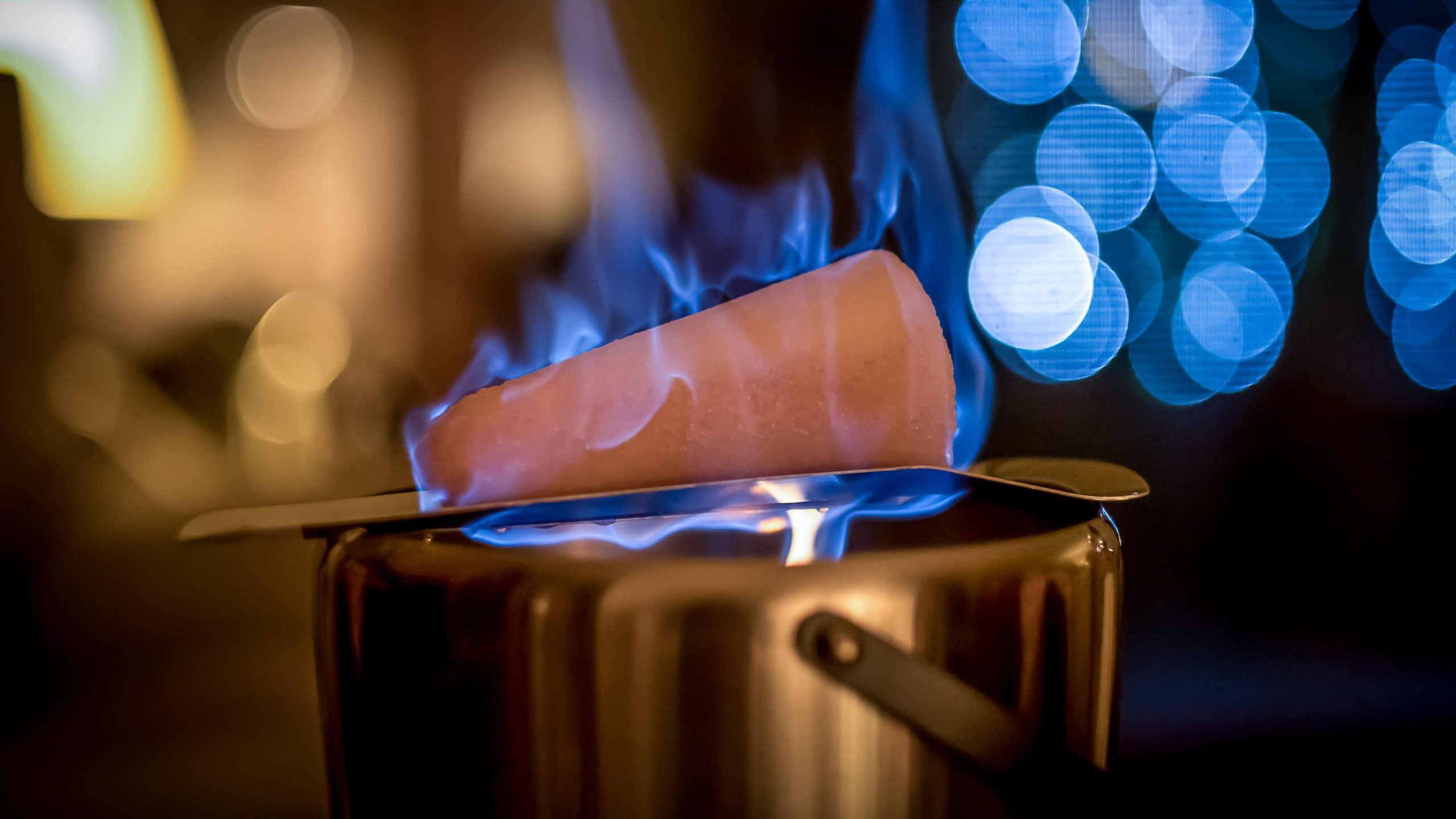 Ein Topf mit Feuerzangenbowle, auf dem ein brennender Zuckerhut liegt.