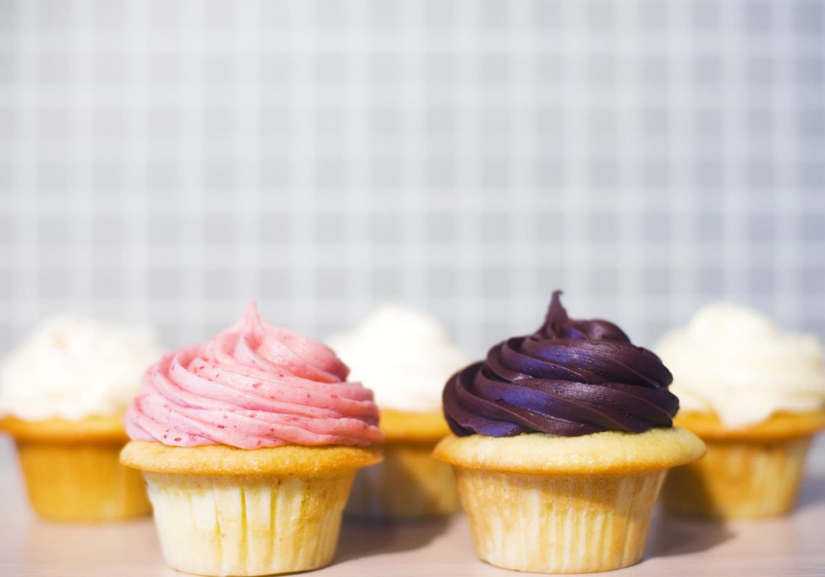 Fünf Cupcakes mit bunten Creme-Hauben stehen vor einem hellen Hintergrund.