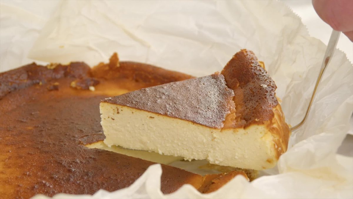 Ein Stück baskischer Käsekuchen liegt auf einem weißen Teller.