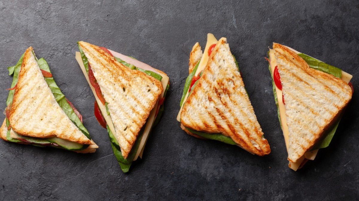 Mehrere Club-Sandwichs mit Schinken, Käse und Salat auf Schiefer-Platte