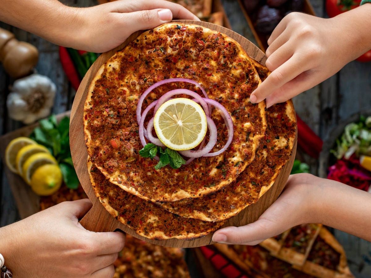 Mehrere türkische Pizzen, genannt Lahmacun, liegen zum Verzehr auf einem Holzbrett übereinander.