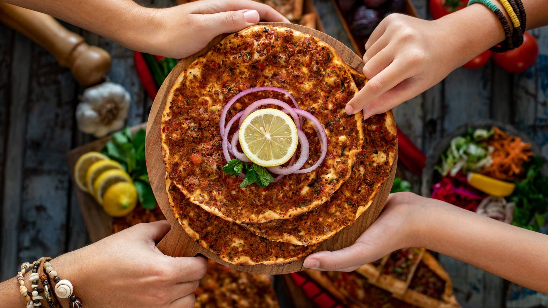 Mehrere türkische Pizzen, genannt Lahmacun, liegen zum Verzehr auf einem Holzbrett übereinander.