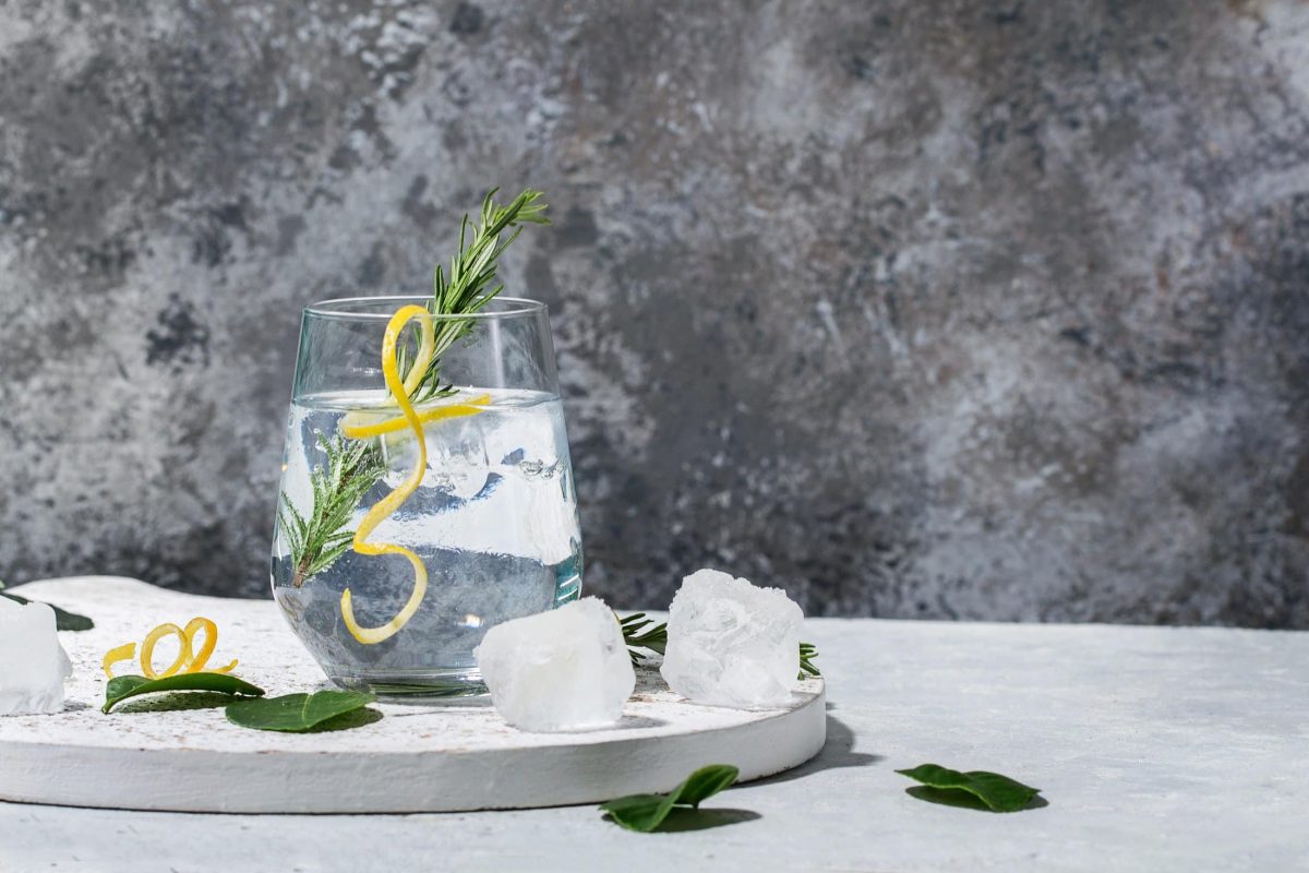 Gin Tonic in einem Glas, serviert mit Eiswürfeln, Rosmarin und Zitrone