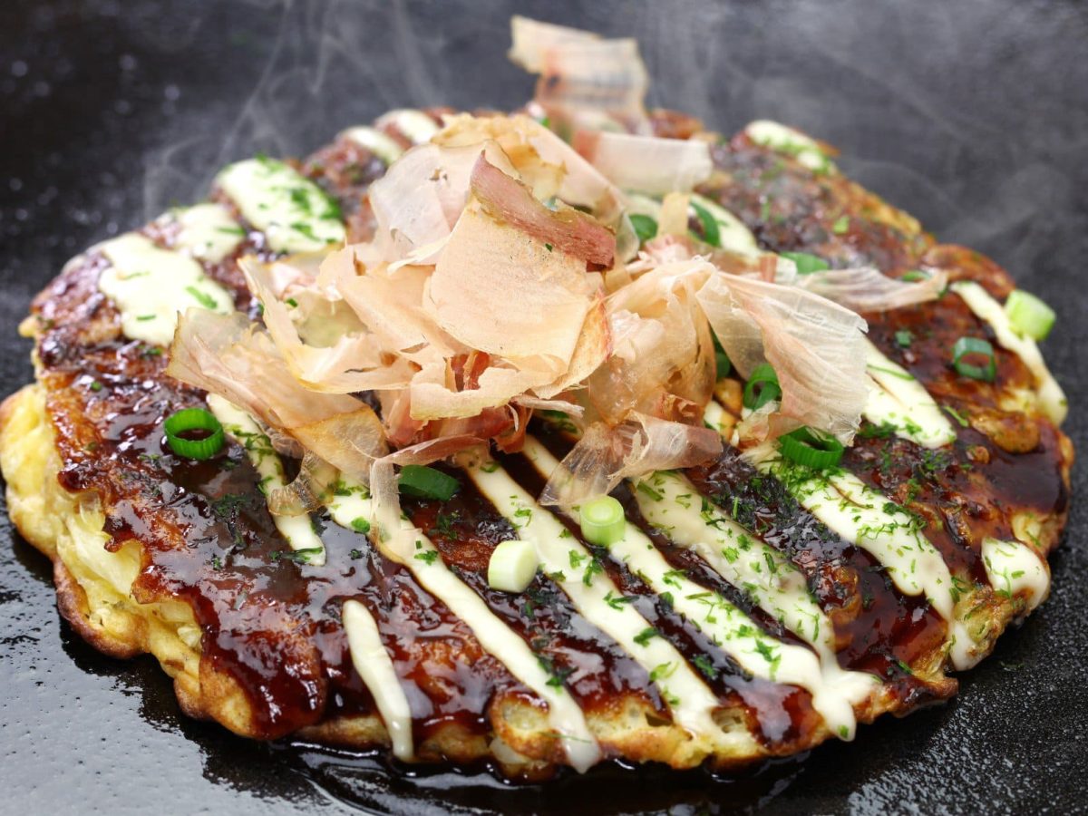 Okonomiyaki mit Bonito-Flocken auf heißer Eisenplatte