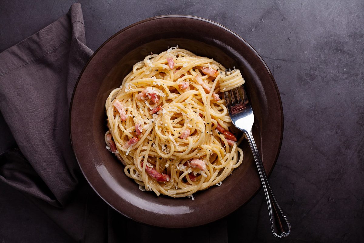 Spaghetti Carbonara auf dunklem Teller.