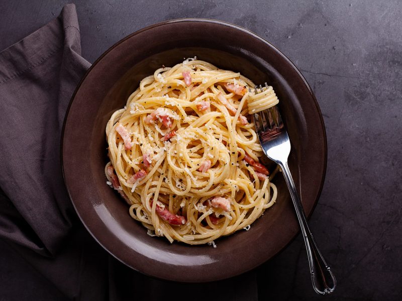 Spaghetti Carbonara auf dunklem Teller.