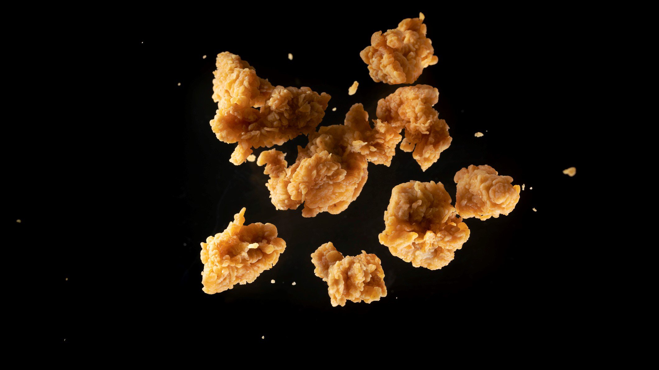 KFC Popcorn Chicken selbstgemacht und frittiert in der Luft eingefangen mit High Speed Kamera vor schwarzem Hintergrund.