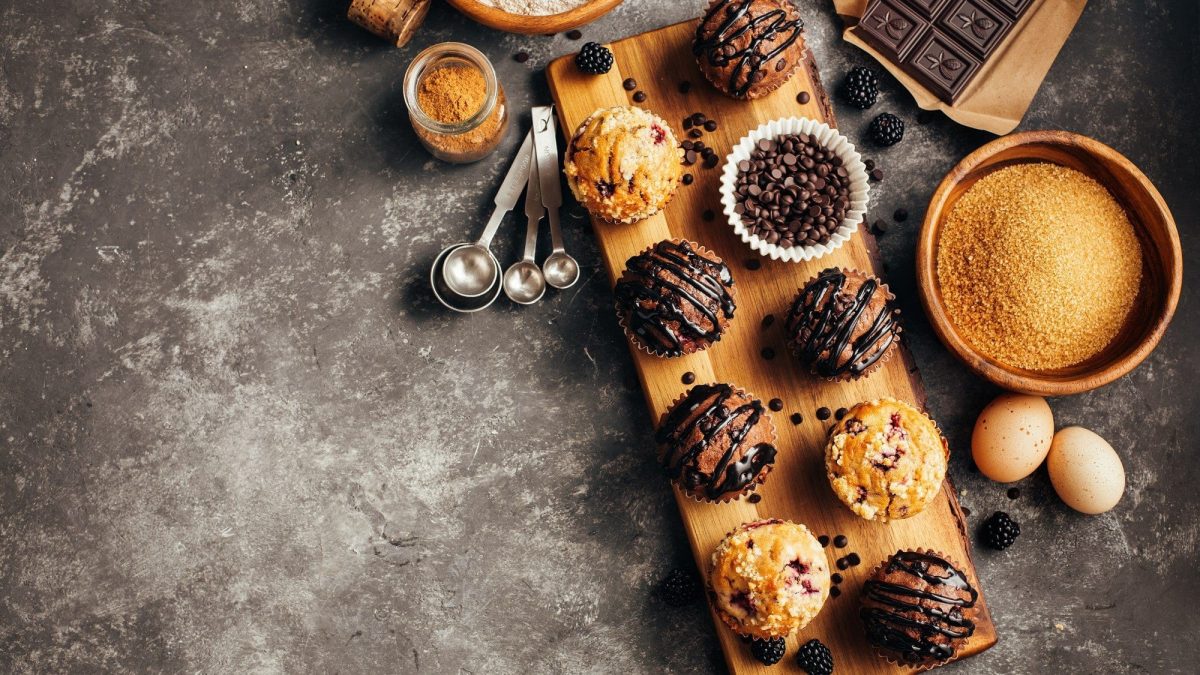 Auf einem Holzbrett liegen verschiedene Sorten von Muffins. Sie sind unterschiedlich dekoriert und Zeigen die Vielfalt von Muffins.