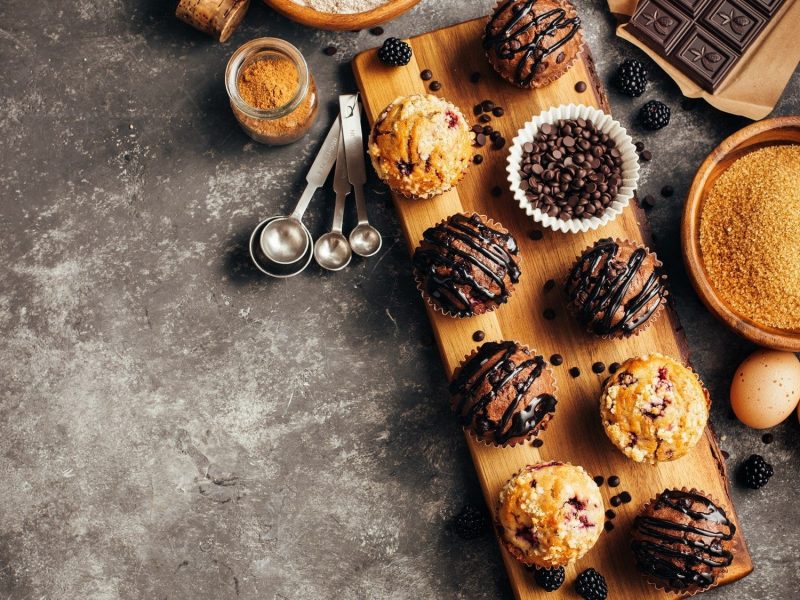 Auf einem Holzbrett liegen verschiedene Sorten von Muffins. Sie sind unterschiedlich dekoriert und Zeigen die Vielfalt von Muffins.