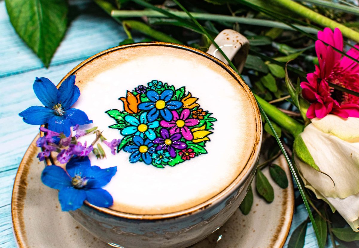 Eine Tasse Kaffee mit buntem Blumenmotiv auf dem Milchschaum.