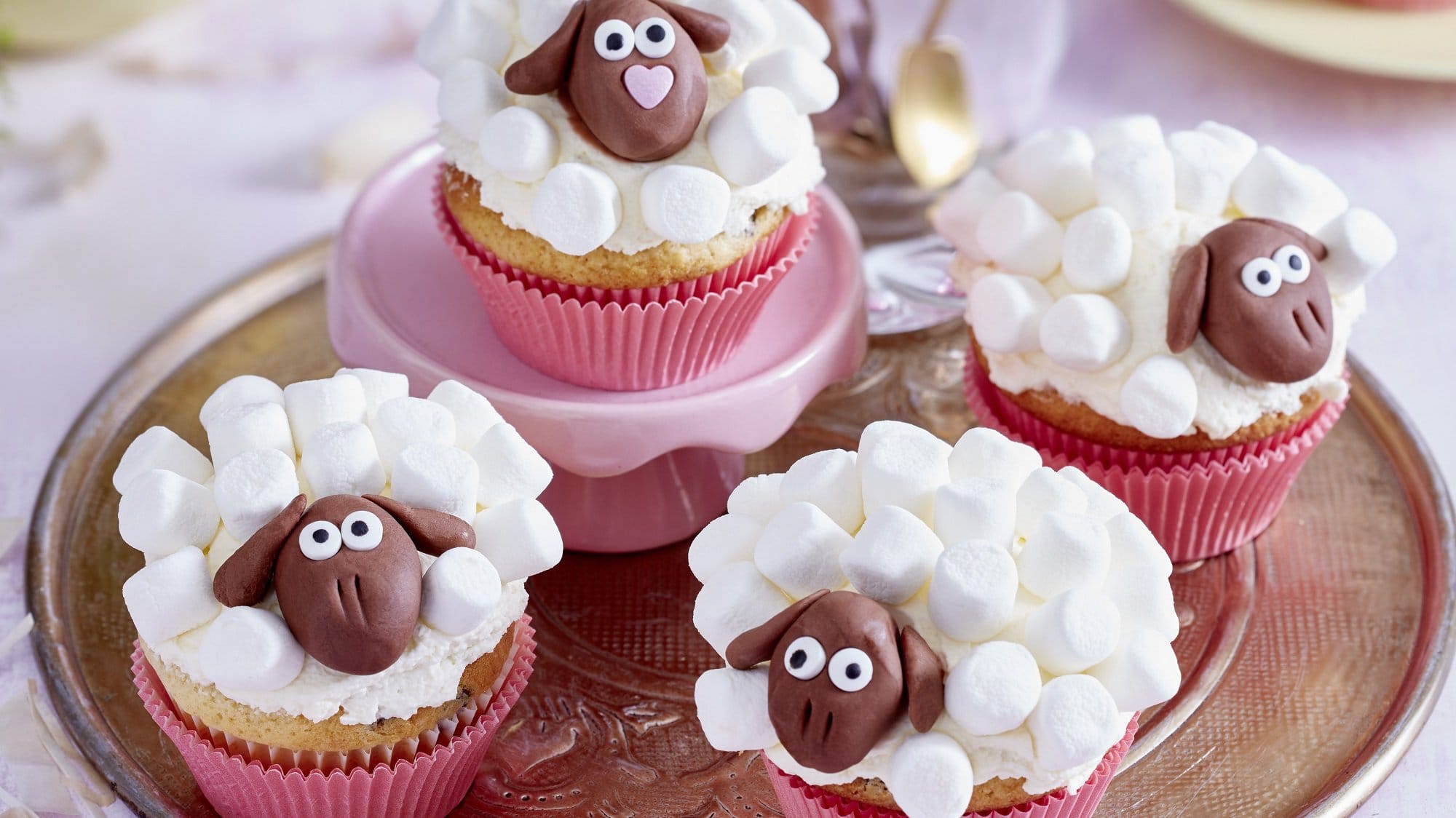Auf einem Tablett stehen vier Schäffchen Muffins. Sie sind mit Marshmallows und Fondant dekoriert.