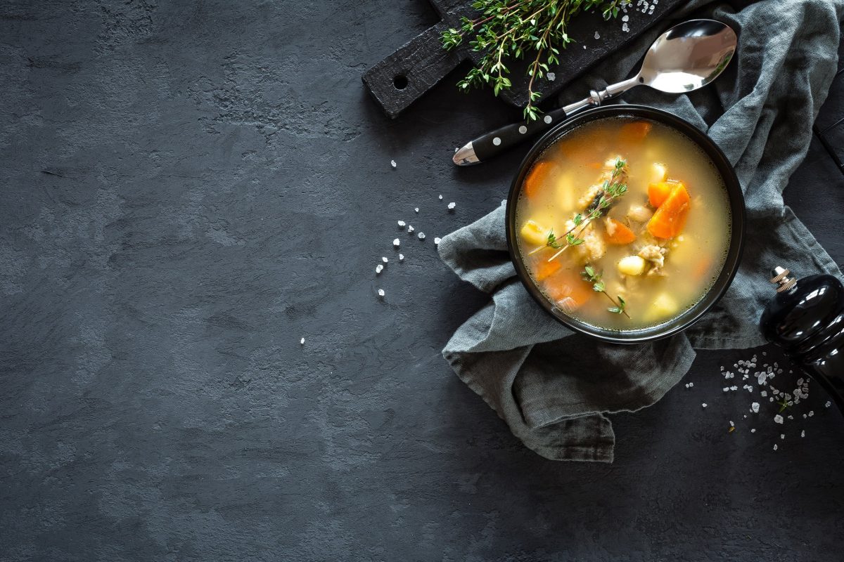Suppe in schwarzer Schale auf dunkelblauem Untergrund.