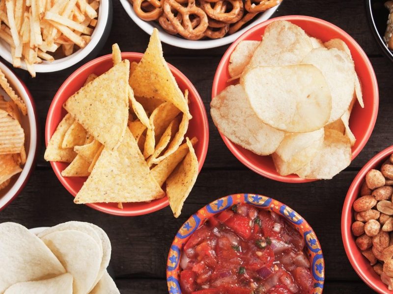 Chips, Dips und Fritten: auf dem Tisch stehen unterschiedliche Snacks in kleinen Schälchen.