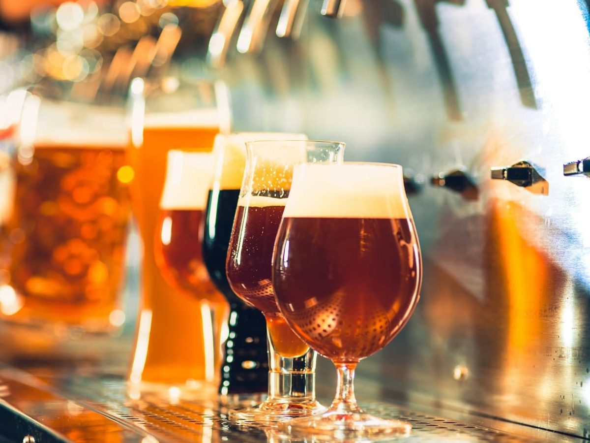 Zum Tag des Deutschen Bieres verschiedene Biersorten in Gläsern auf Theke unter Zapfhahn. Frontalaufnahme.