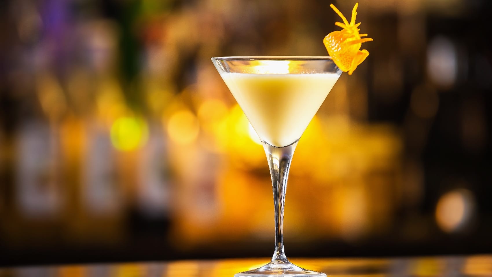 Ein Martini-Glas vor leuchtendem Hintergrund mit gelb-weißer Flüssigkeit.