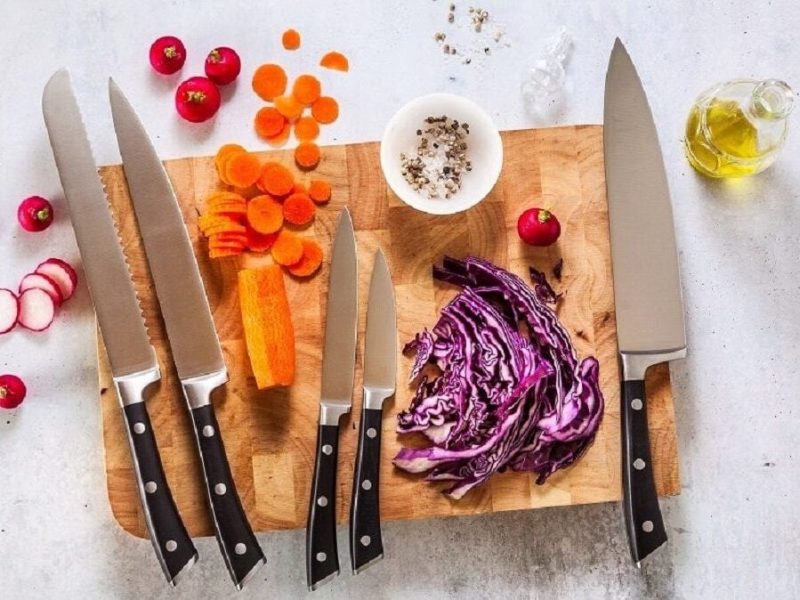 Gute Küchenmesser liegen auf einem Küchenbrett. Daneben liegen viele Gemüseteile.