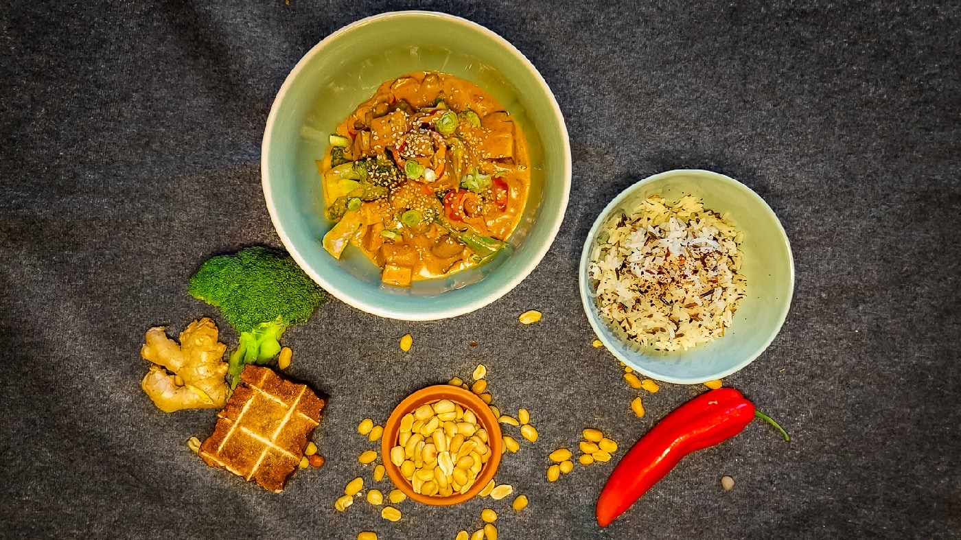 Draufsicht auf das Curry-und Reisgericht. Mit Erdnuss und Miso am Rand des Bildes.