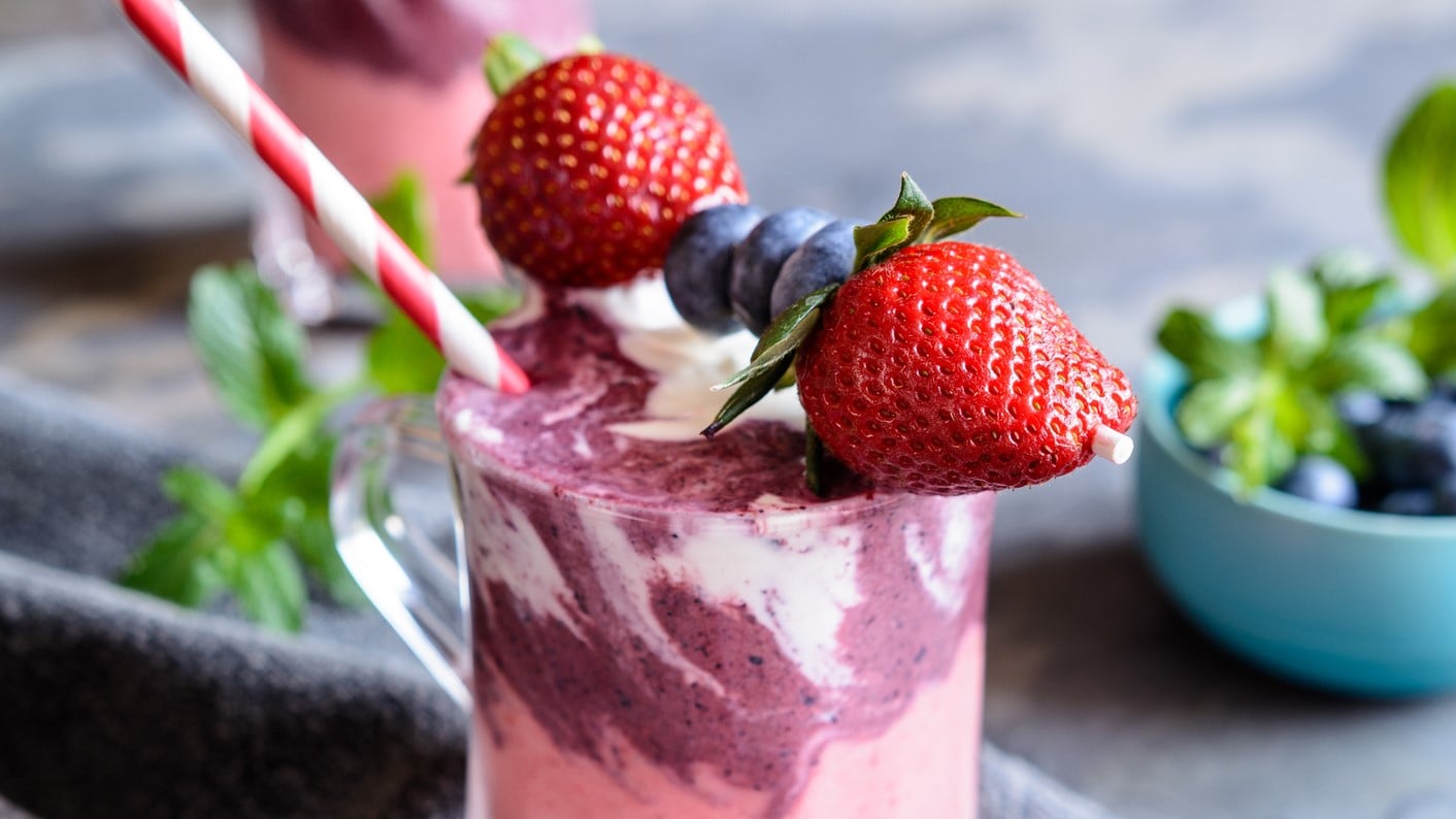 Erdbeer-Heidelbeer-Smoothie mit Joghurt mit frischen Früchten serviert.