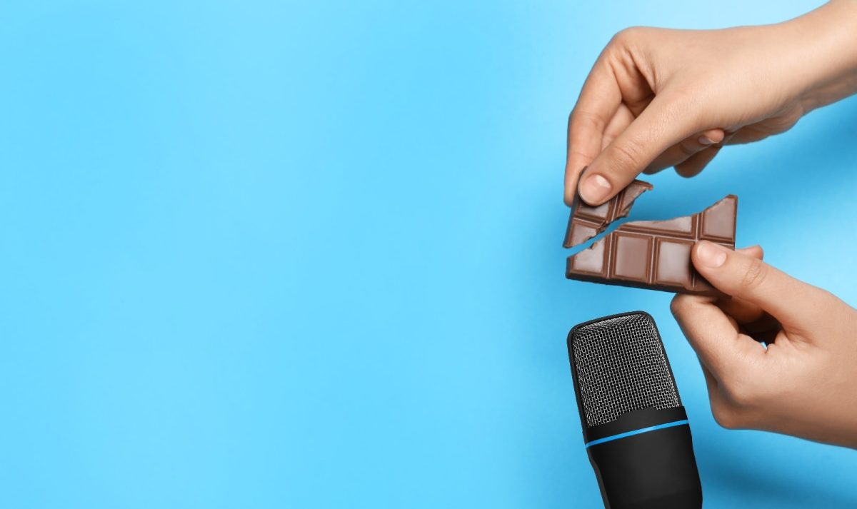 Zwei Hände, die eine Tafel Schokolade vor einem Mikrofon zerbrechen, um ASMR Food zu machen