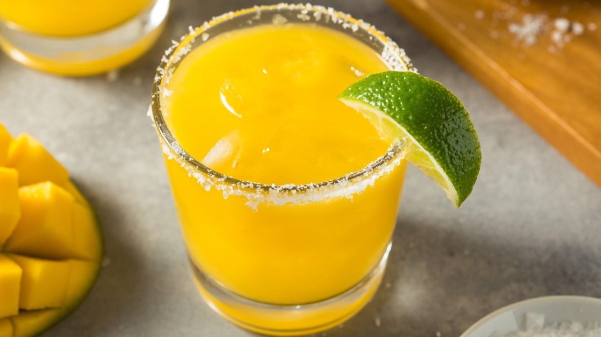 Ein Glas Mango-Margarita neben einer frischen Mango
