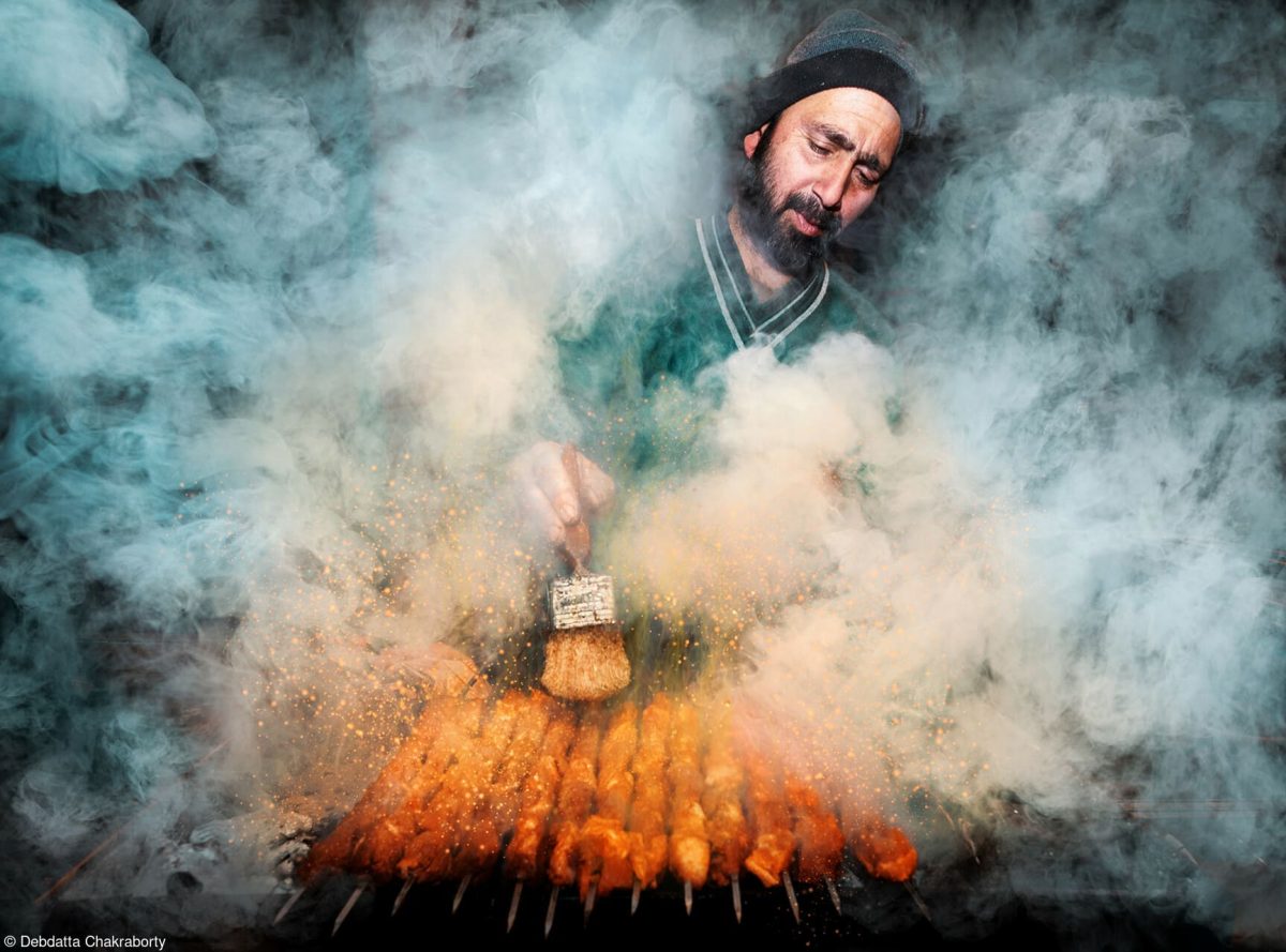 Das Gewinnerfoto vom World's Best Food Photography Wettbewerb: Ein Mann steht, von Rauch umwabert, vor einem Kebab-Grill und bereitet Fleischspieße zu.