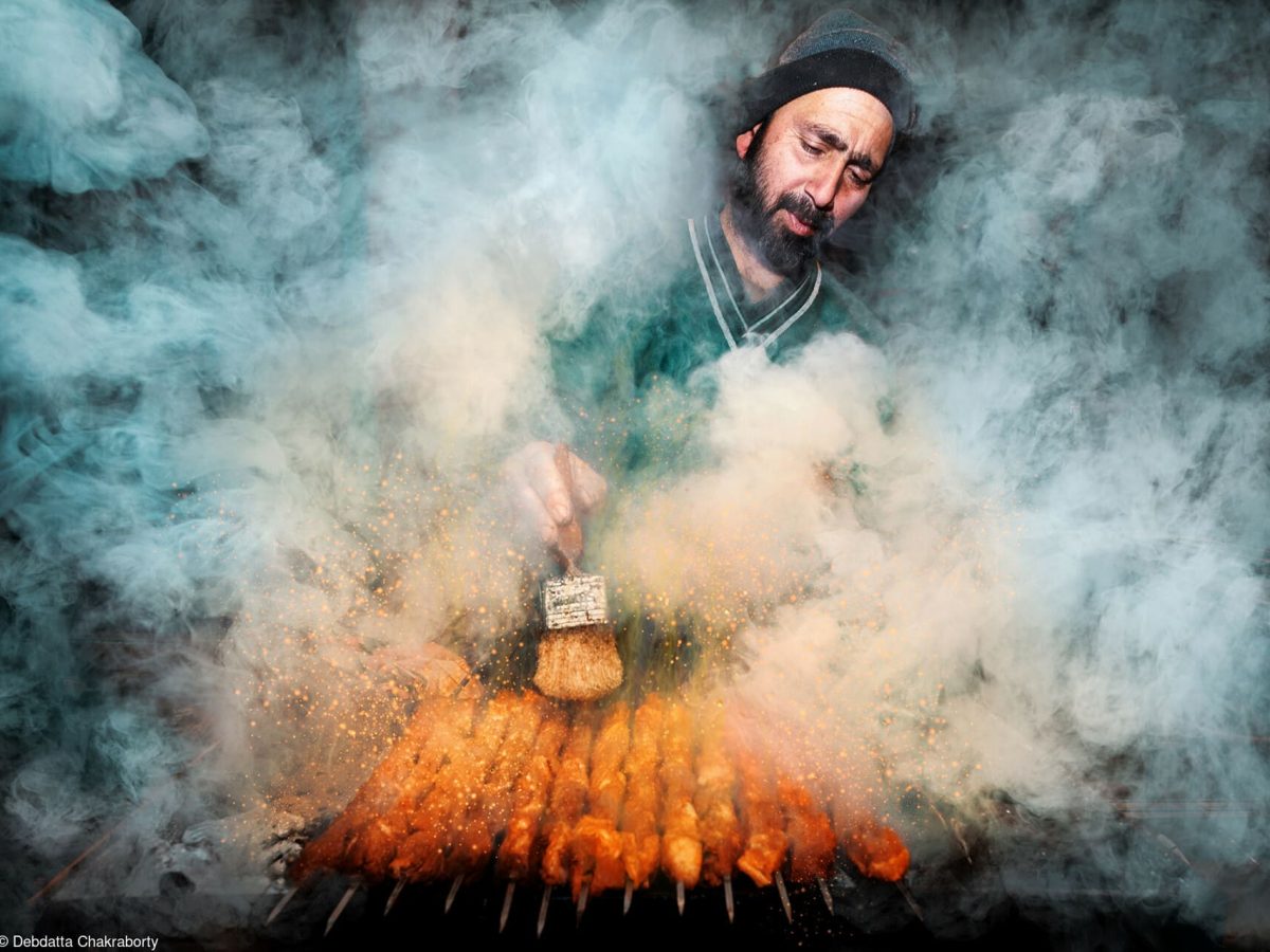 Das Gewinnerfoto vom World's Best Food Photography Wettbewerb: Ein Mann steht, von Rauch umwabert, vor einem Kebab-Grill und bereitet Fleischspieße zu.