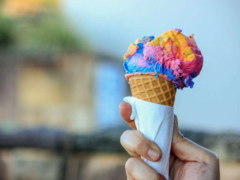 Ice Cream & Sweets Festival N°1 Hamburg: Eine Frau hält eine Eiswaffel mit einer Kugel Eis in Regenbogenfarben.