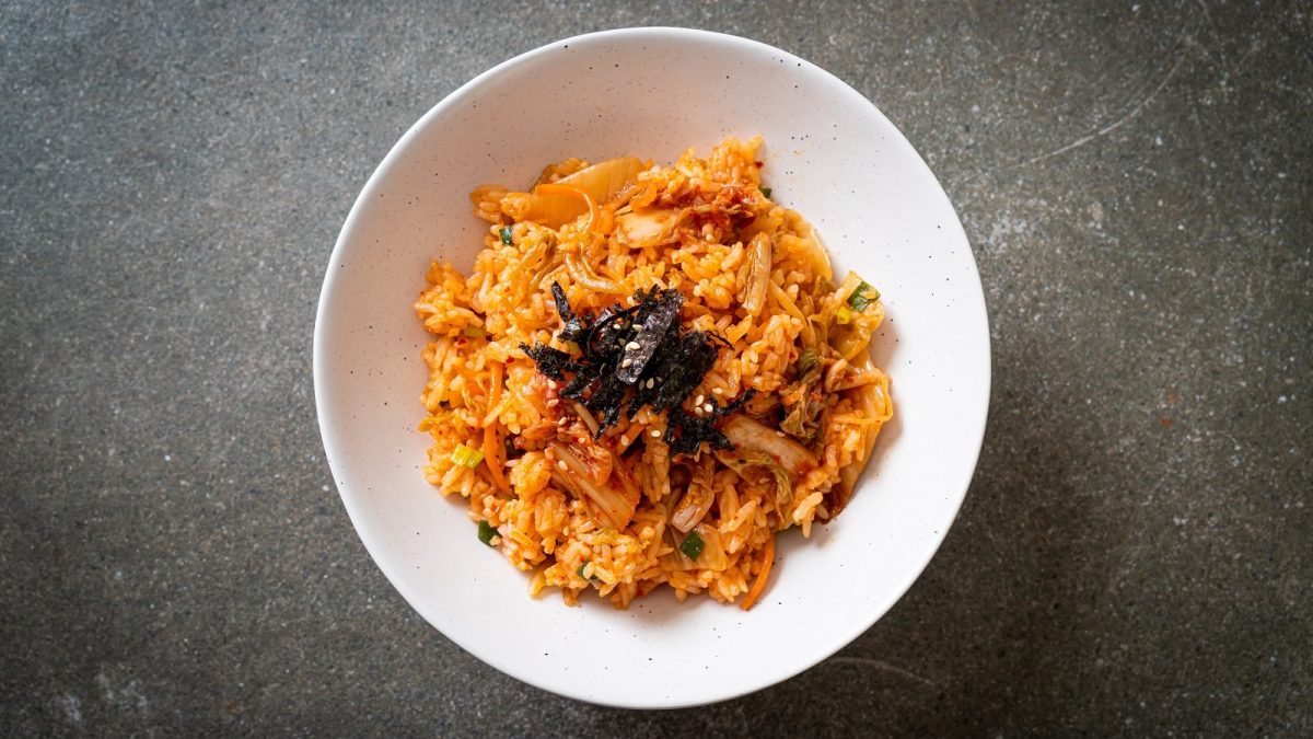 Ein Teller mit Kimchi Fried Rice und Nori-Streifen in einer weißen Schüssel auf grauem Hintergrund